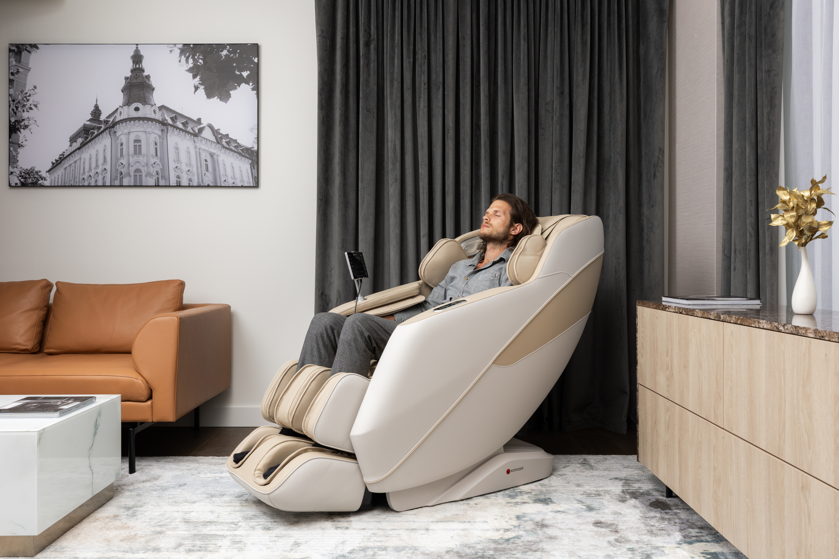 A man relaxing with his eyes closed in a beige Komoder massage chair in an elegant living room